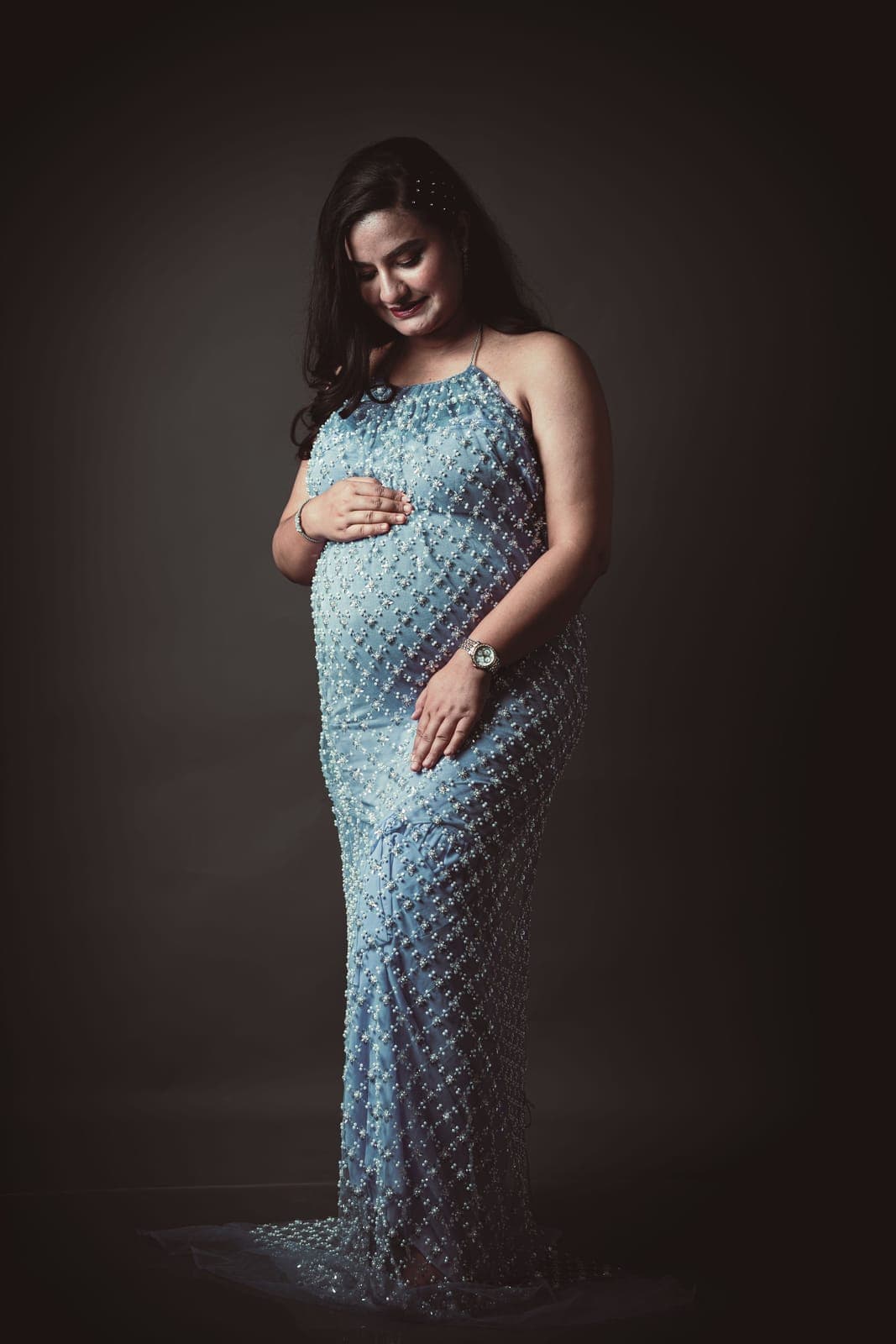 Retrato de estudio de una mujer embarazada con vestido azul de lentejuelas