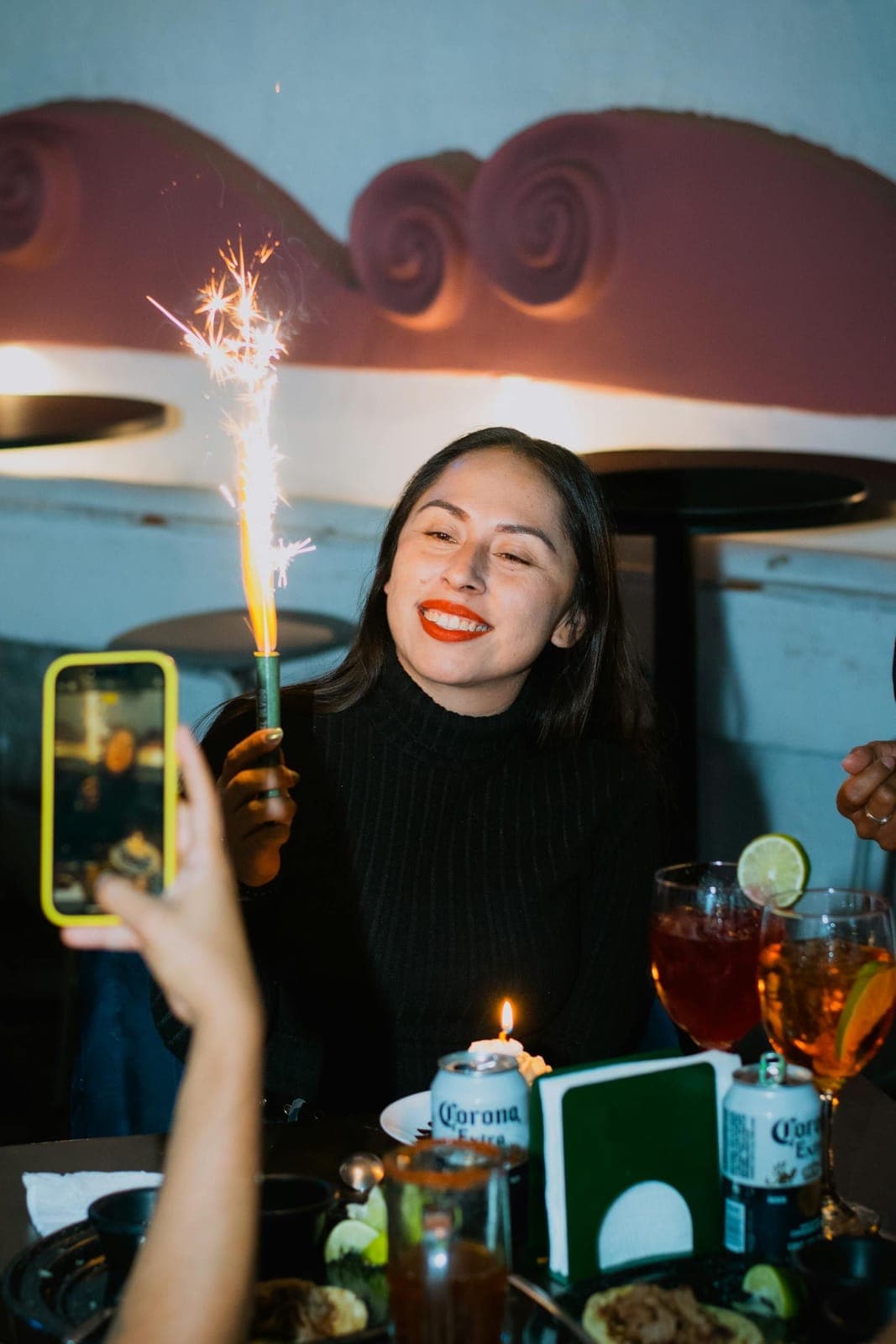 Joven sonriendo con una bengala de cumpleaños en una mesa de fiesta