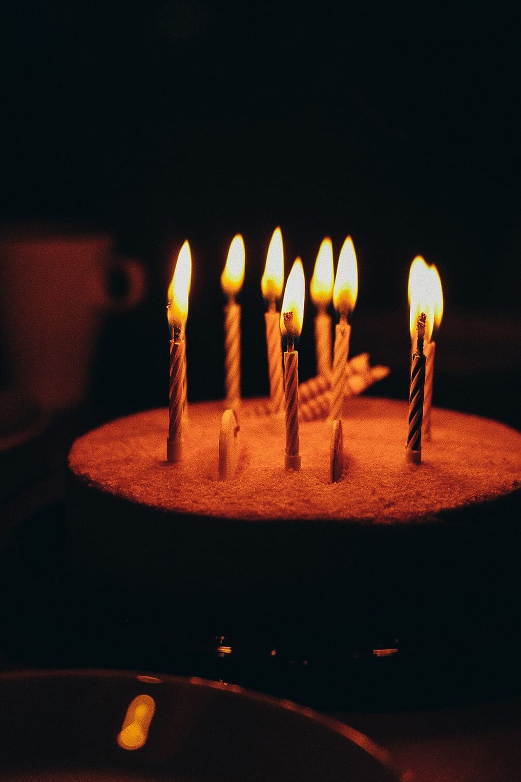 Velas encendidas sobre un pastel de cumpleaños en la oscuridad