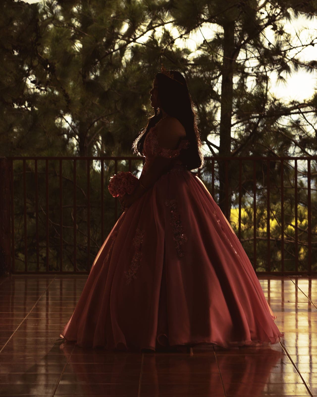 Silueta de una joven con vestido de gala en un balcón al atardecer